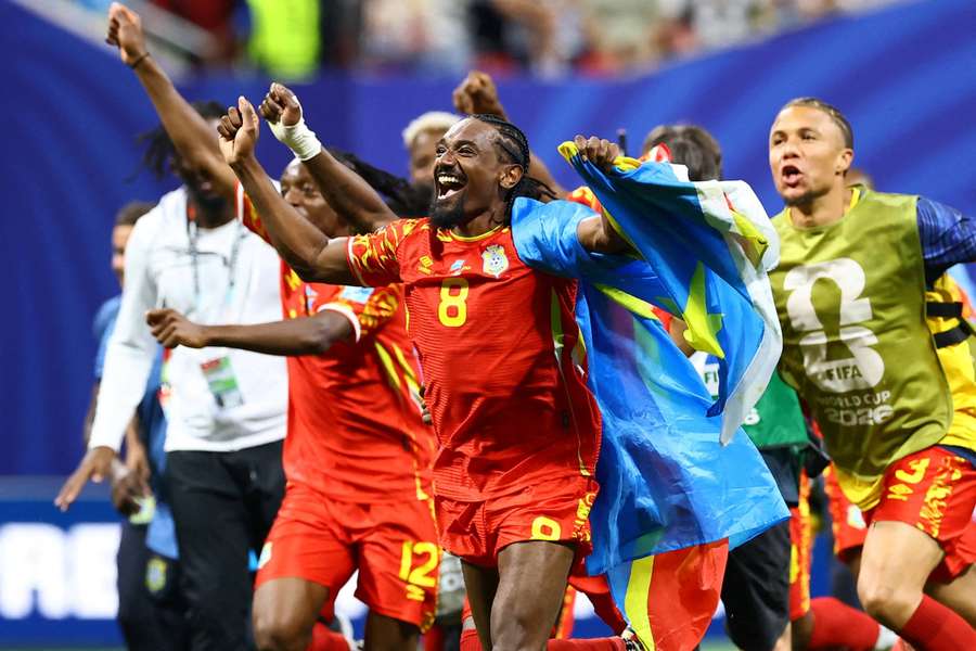 DR Congo's Samuel Moutoussamy celebrates with their national flag as they qualify for the knockout stages of the World Cup