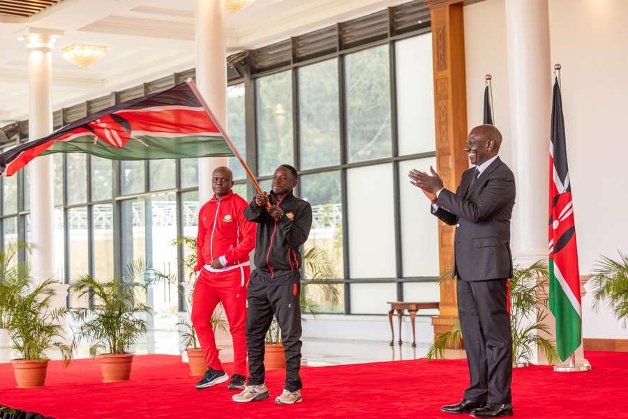 Kenya captain Baron Ochieng receives the flag from President Ruto