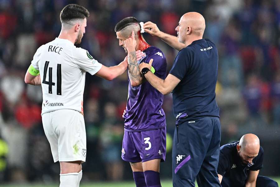 Cristiano Biraghi receives medical attention after being hit by an object thrown from the stands