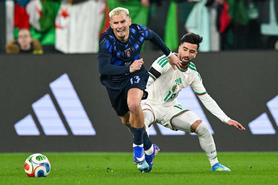 Varela y Amoura luchan por un balón 