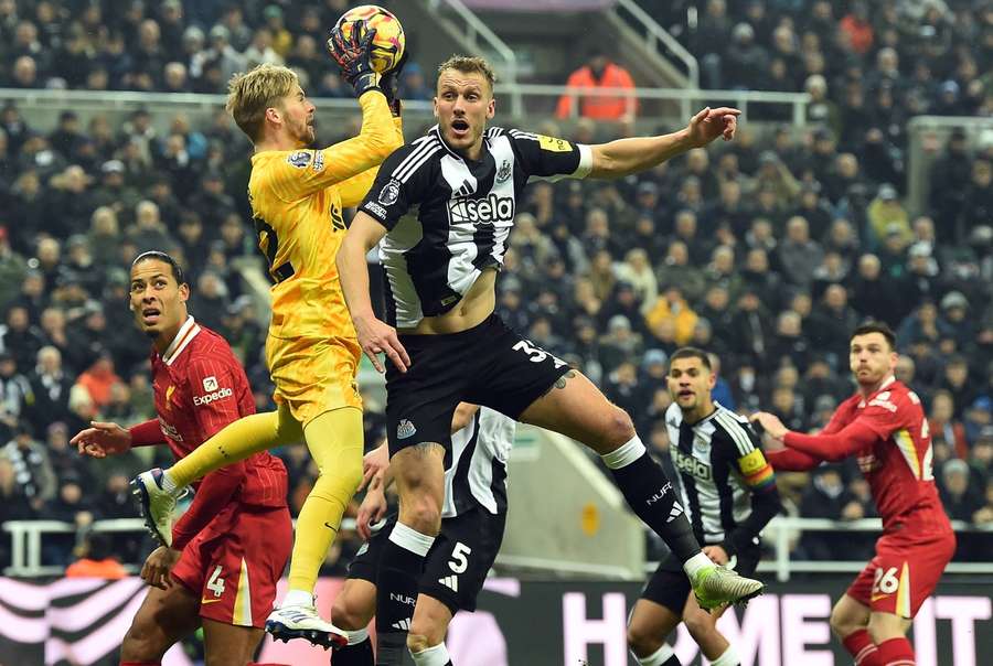 Liverpool's goalkeeper Caoimhin Kelleher (L) in action against Newcastle United's Dan Burn (R)