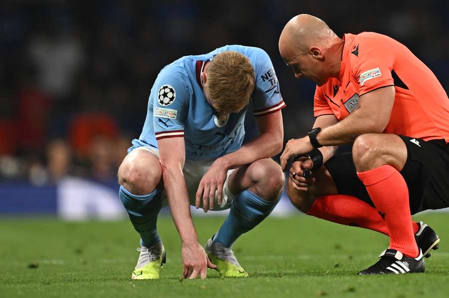 Szymon Marciniak praat met Kevin De Bruyne die het veld moet verlaten