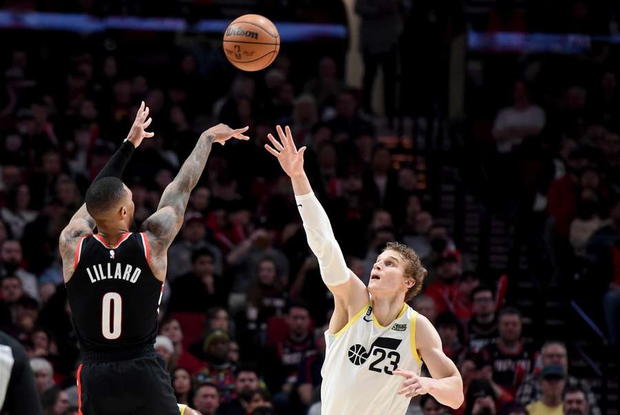 Trail Blazers' Damian Lillard scoort een driepunter over Jazz' Lauri Markkanen heen