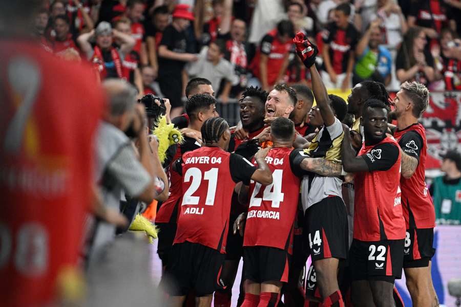 Leverkusen-spelers verzamelen zich rond penaltyheld Lukas Hradecky