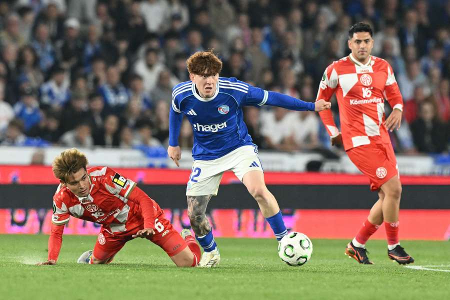 Le milieu argentin de Strasbourg, Valentin Barco, à la lutte avec le Japonais Kaishu Sano (Mayence) lors du quart de finale retour de Ligue Conférence, le 16 avril 2026 à la Meinau.