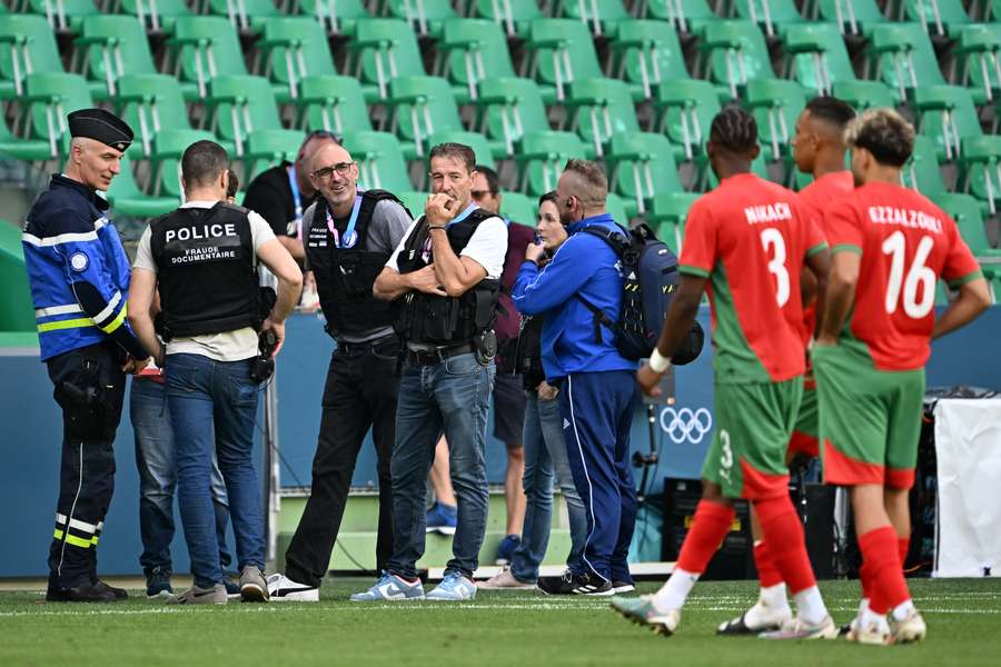 Police officers stand by the pitch as Morocco's players (R) come back in an emptied stadium