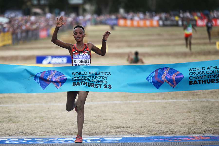 Chebet passeert de finish en verovert de wereldtitel. Op de achtergrond is de ingestortte Gidey te zien