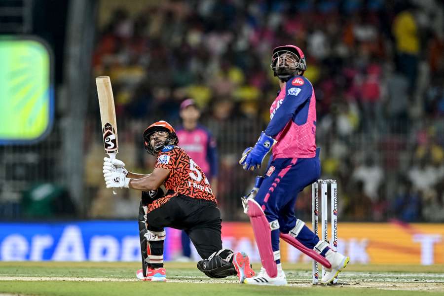 Sunrisers Hyderabad's Rahul Tripathi (L) watches the ball after playing a shot as Rajasthan Royals' wicketkeeper and captain Sanju Samson looks on