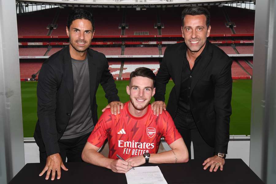 Declan Rice, centre, signs his contract flanked by Mikel Arteta, left, and Edu
