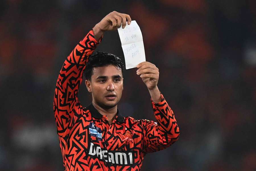 Sunrisers Hyderabad's Abhishek Sharma holds up a note for the fans after reaching his century