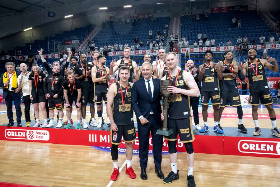 Koszykarze Trefla Jakub Schenk (L) i Jarosław Zyskowski (P) oraz dyrektor sportowy reprezentacji i prezes PLK Łukasz Koszarek (C) z trofeum.