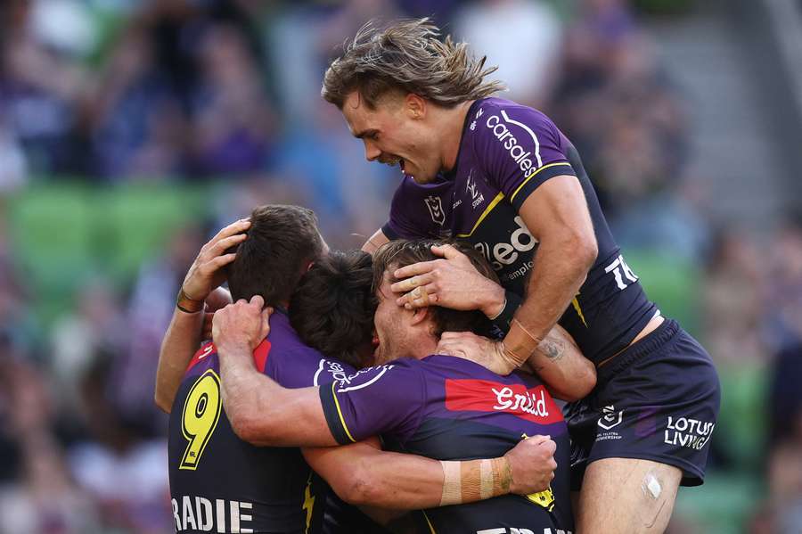 Melbourne Storm players celebrate one of their 11 unanswered tries against Wests Tigers.