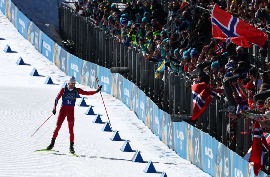 Johannes Hoesflot Klaebo of Norway celebrates with fans before crossing the finish line to win the gold medal