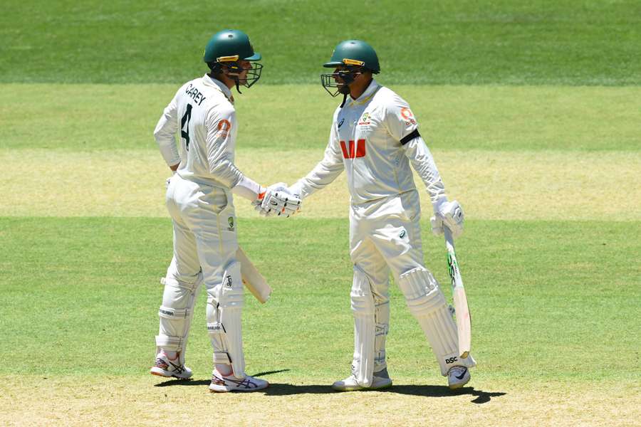 Usman Khawaja (R) shakes hands with batsman Alex Carey
