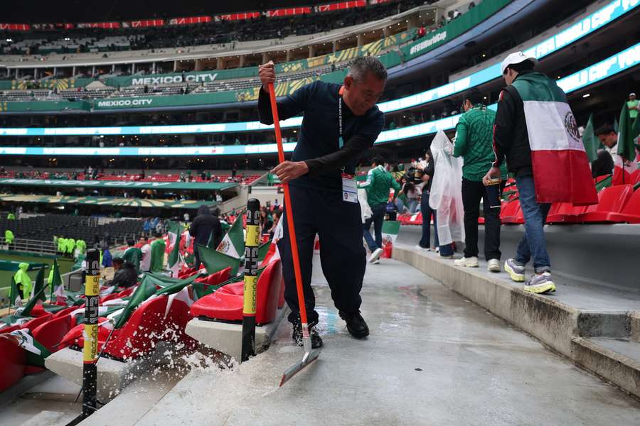 A staff member sweeps away water inside the Estadio Azteca on matchday.