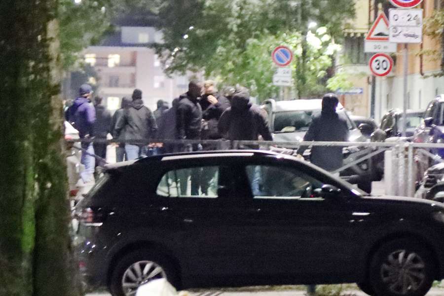 Groups of men dressed in black are pictured at the scene of a fight between PSG and AC Milan supporters, late last night in the Navigli area of Milan