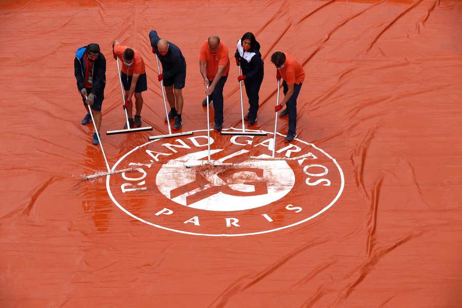  Grondpersoneel ruimt water op van een cover op Roland Garros