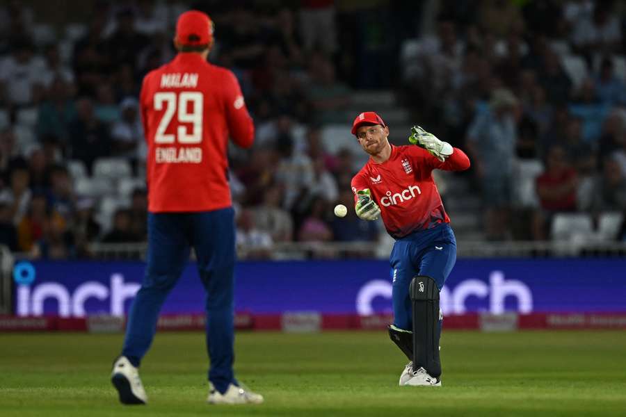 England's Jos Buttler (R) fields the ball to England's Dawid Malan during the fourth T20 international cricket match between England and New Zealand