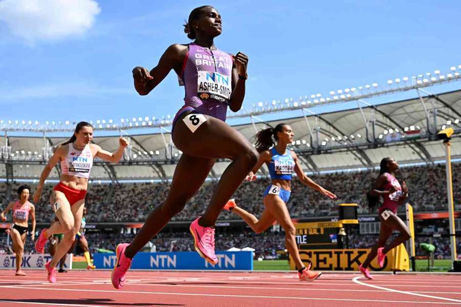 Dina Asher-Smith crosses over the line to reach the semi-finals of the 200m