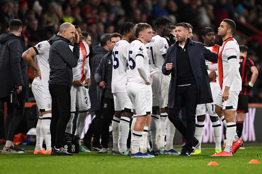 Rob Edwards and players of Luton Town react as a break in play takes place as Tom Lockyer (not pictured) receives medical treatment