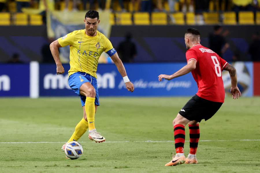 Cristiano Ronaldo de la Al Nassr în acțiune cu Dzenis Beganovic de la FC Istiklol
