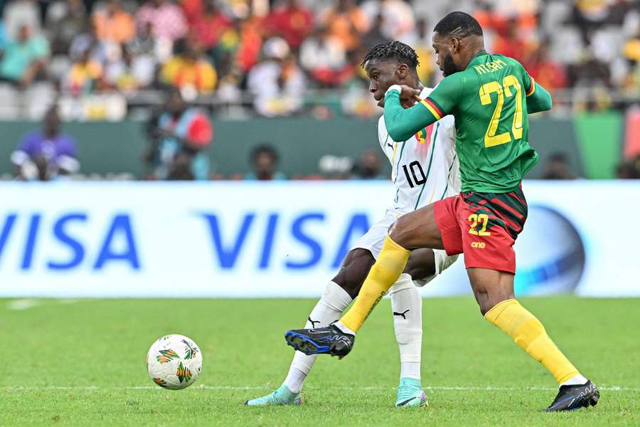 Guinea's Moriba Kourouma (C) fights for the ball with Cameroon's Olivier Ntcham
