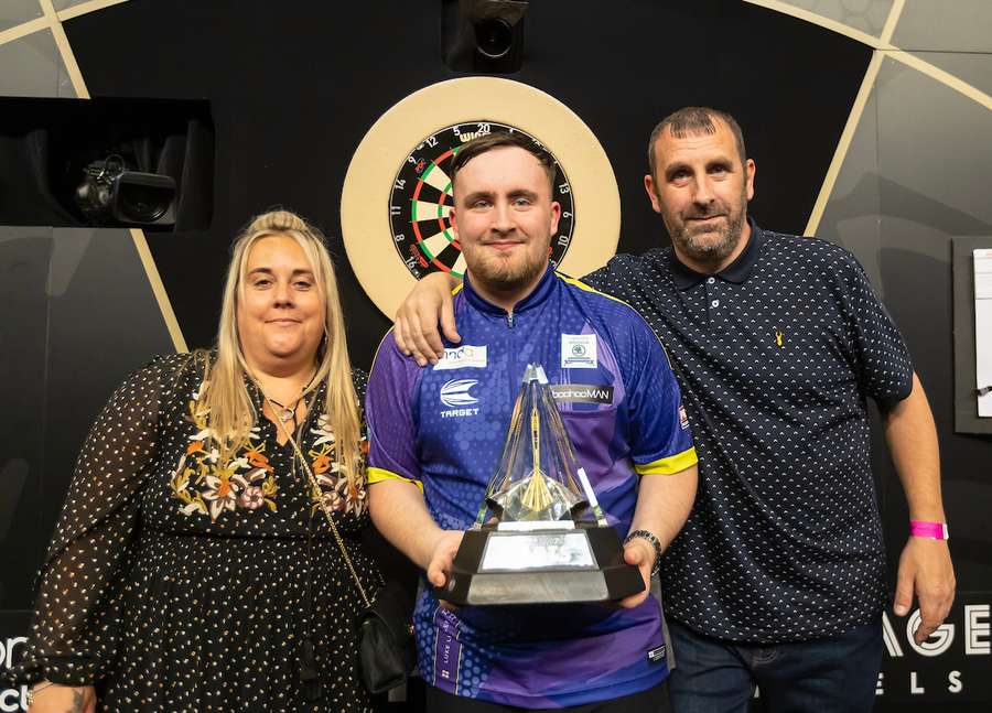 Luke Littler poses with the Premier League trophy alongside his family