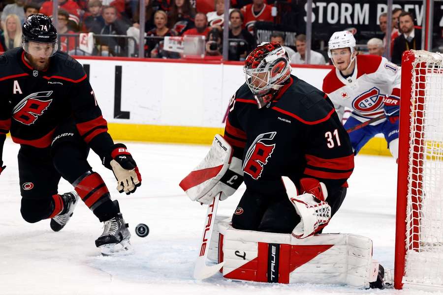 The puck bounces between Carolina Hurricanes goaltender Frederik Andersen and Jaccob Slavin with Montreal Canadiens' Cole Caufield (13) nearby The puck bounces between Carolina Hurricanes goaltender Frederik Andersen and Jaccob Slavin with Montreal Canadiens' Cole Caufield (13) nearby
