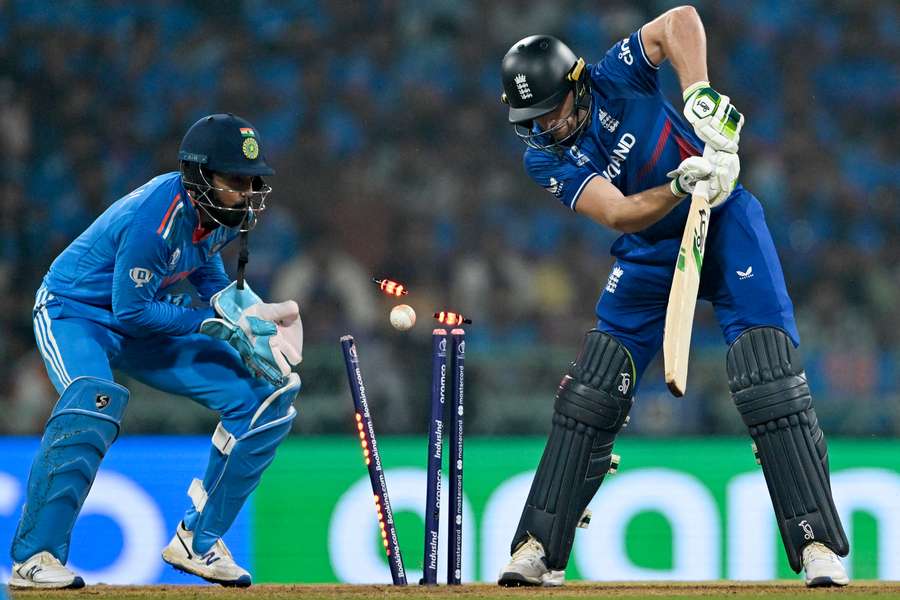 England's captain Jos Buttler (R) is clean bowled as India's KL Rahul watches
