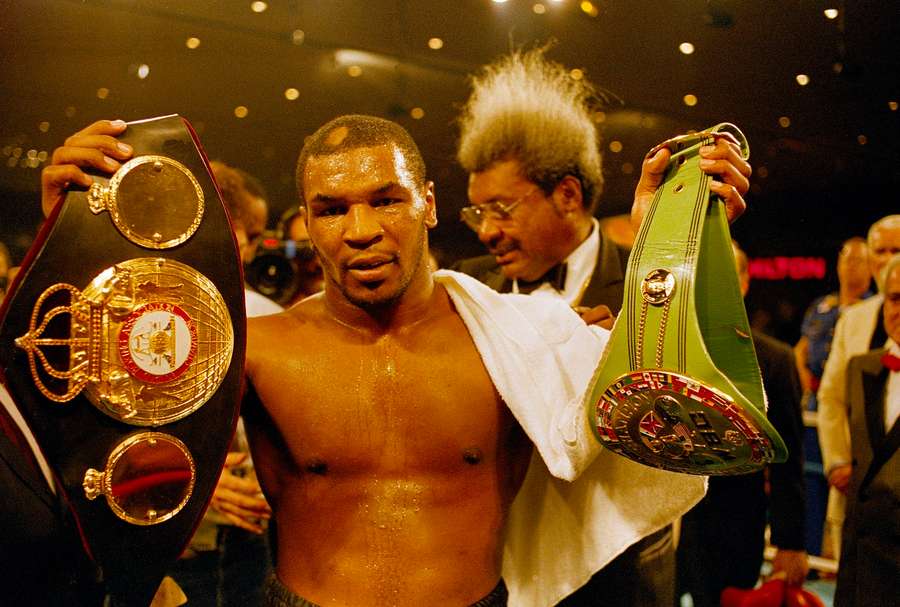 Tyson holds up two of the three heavyweight championship belts