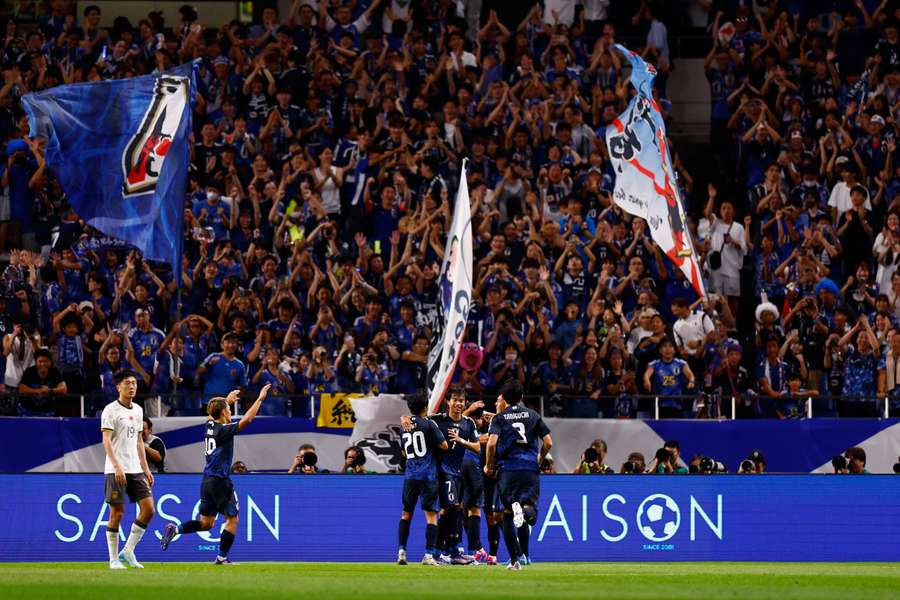 Japan's Takumi Minamino celebrates scoring their third goal with teammates