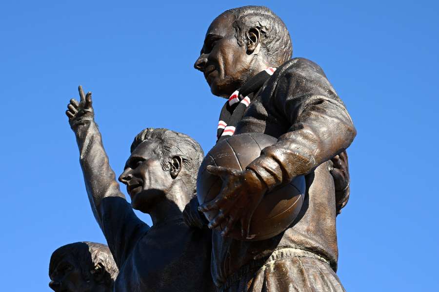 Manchester United scarves are placed in memory of Sir Bobby Charlton on the statue of George Best, Denis Law and Bobby Charlton outside Old Trafford