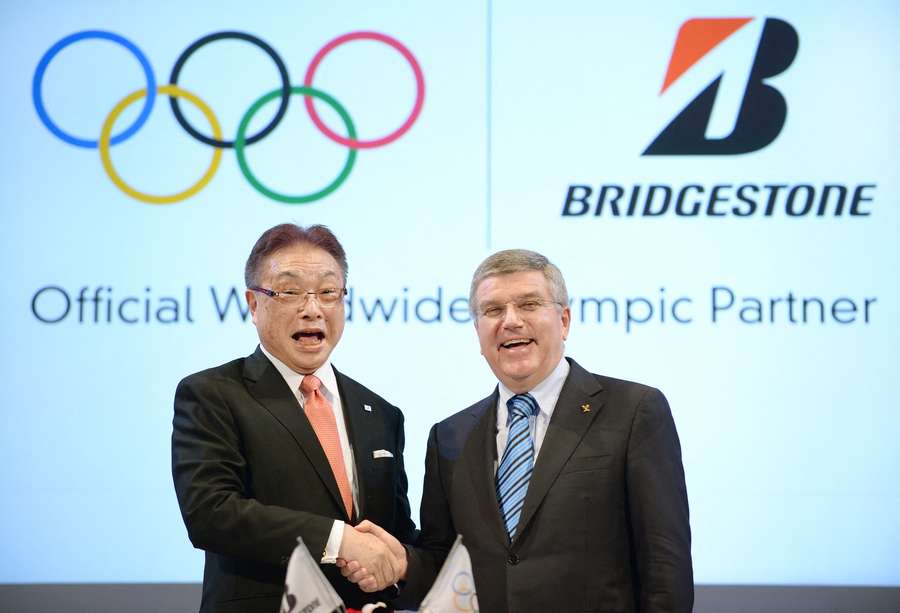 President of the IOC Thomas Bach (R) shakes hands with Chairman and CEO of Japan's tire maker Bridgestone Masaaki Tsuya (L) during a press conference in Tokyo on June 13, 2014.