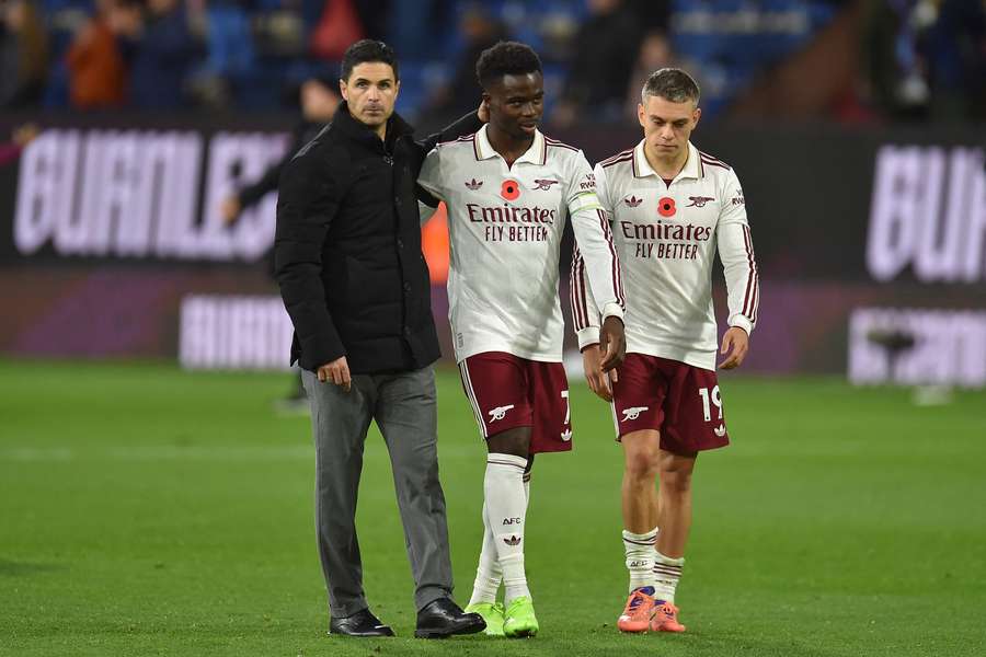 Arsenal's Mikel Arteta, Bukayo Saka, centre, and Leandro Trossard, right, celebrate on the pitch