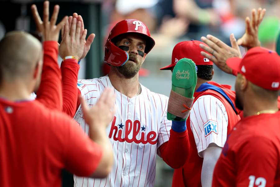 Bryce Harper celebrates scoring a run with his teammates in the dugout (2025)