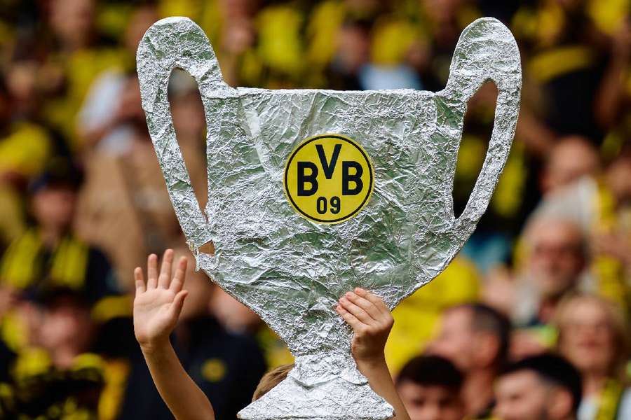 Un fan al Borussiei Dortmund ține în mână o pancartă care imită trofeul Ligii Campionilor