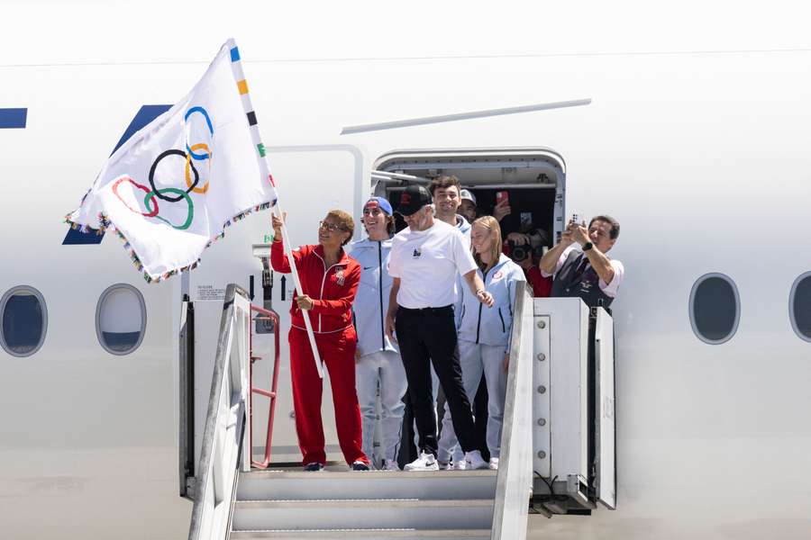 La alcaldesa de Los Ángeles, Karen Bass, ondea la bandera olímpica junto al presidente de LA28, Casey Wasserman.