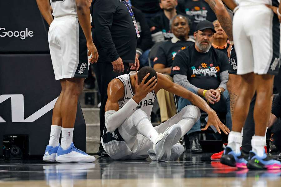 Victor Wembanyama sits on the floor after suffering a head injury from a fall.
