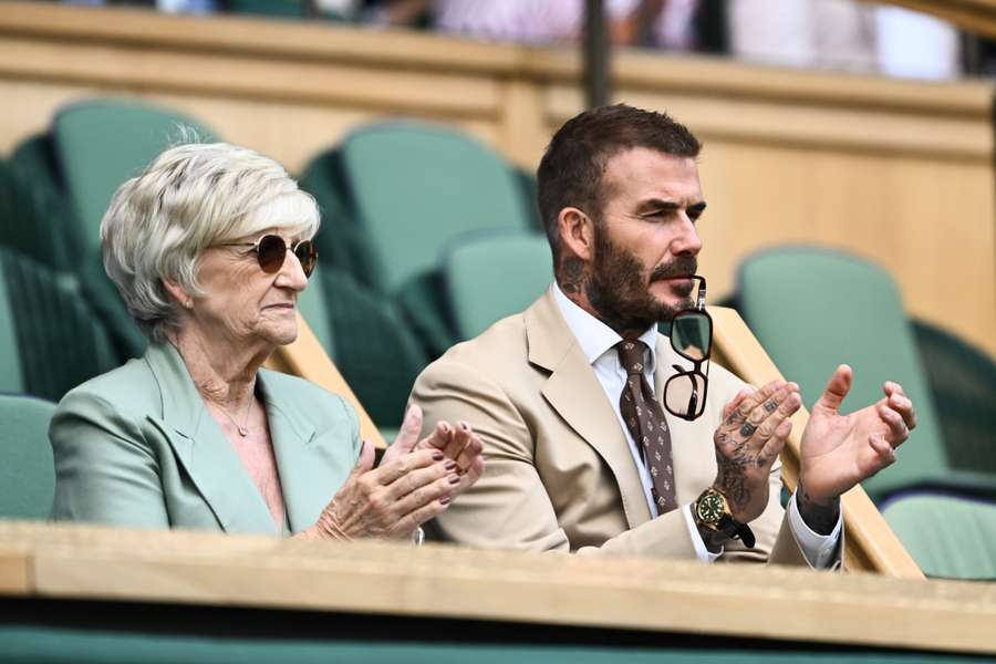 Former British football player David Beckham and his mother Sandra Beckham applaud as they sit in the royal box in Center Court during the women's singles tennis match between Russia's Daria Kasatkina and Britain's Jodie Burrage