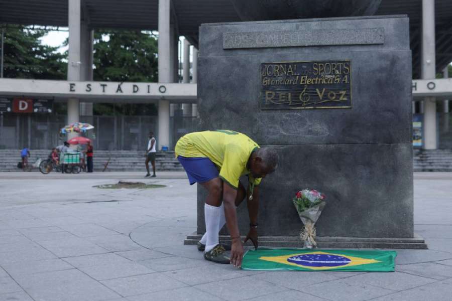 A street artist known as Pele lays down a Brazilian flag in front of Maracana