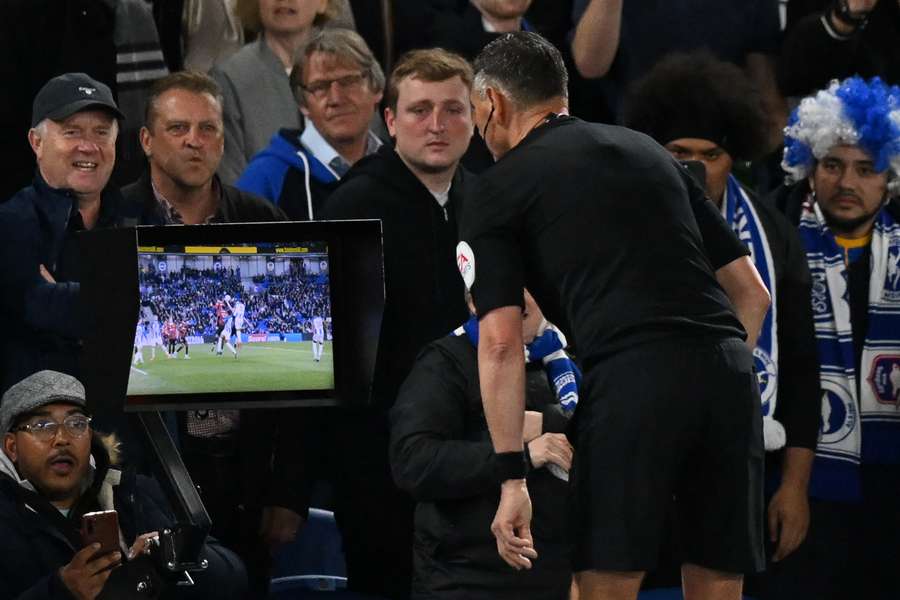 Andre Marriner consults the pitch-side monitor after the VAR advised him to check for a penalty