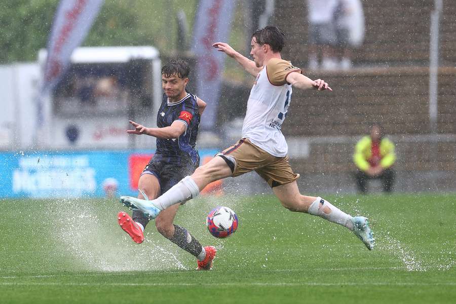 Callan Elliot of Auckland FC and Clayton Taylor of Newcastle compete for the ball at a very soggy Go Media Stadium in Auckland. Callan Elliot of Auckland FC and Clayton Taylor of Newcastle compete for the ball at a very soggy Go Media Stadium in Auckland.