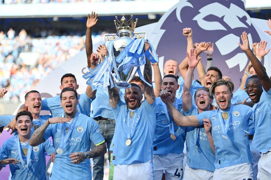 Um adepto do Manchester City levanta um troféu da Premier League em folha