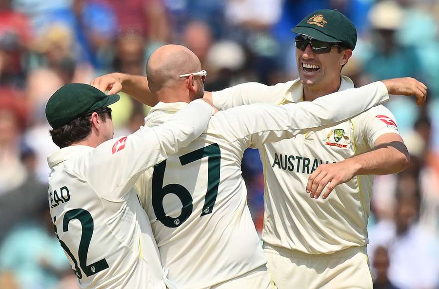 Australia's Nathan Lyon (C) celebrates with teammates Australia's Travis Head (L) and Australia's Pat Cummins (R) after the dismissal of India's Mohammed Siraj for victory during play on day 5 of the ICC World Test Championship cricket final match between Australia and India