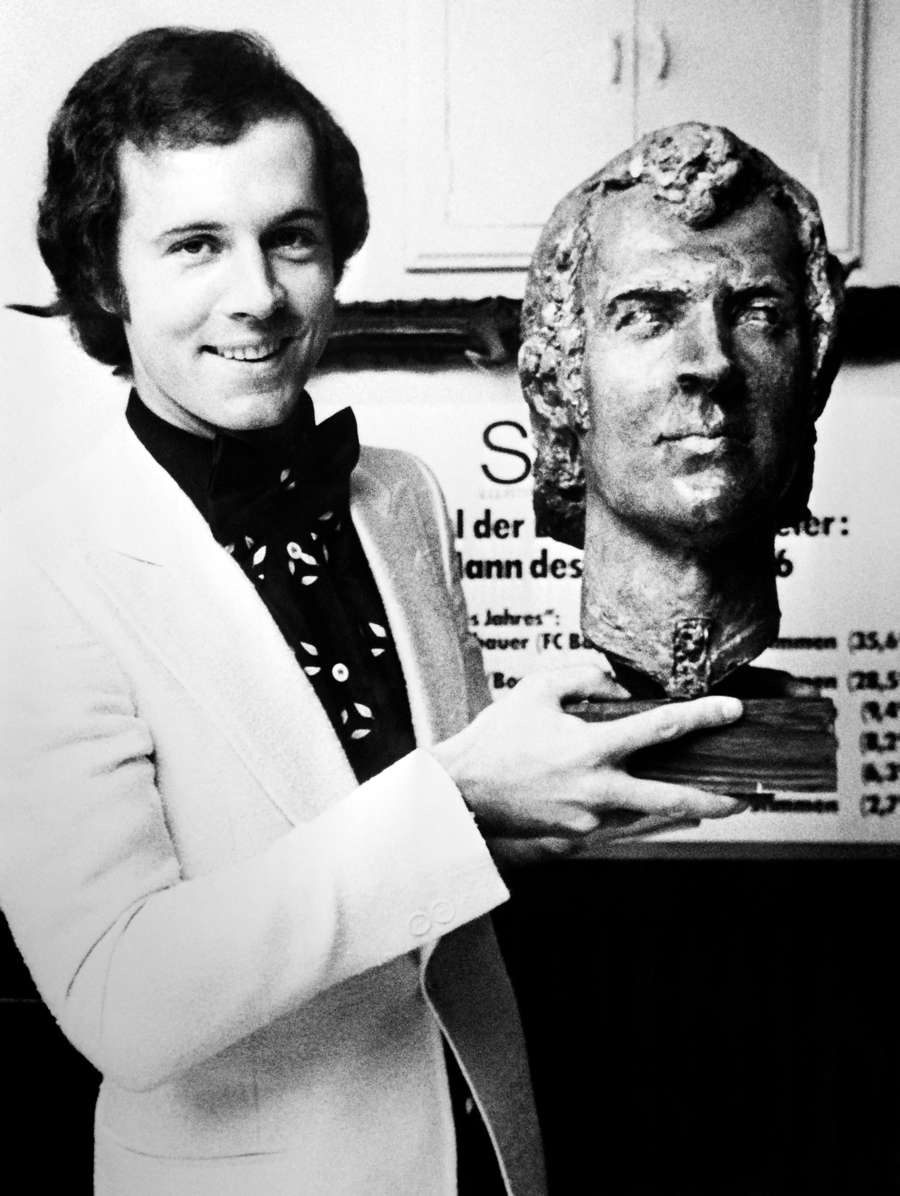 Franz Beckenbauer poses with a sculpture of his effigy, on December 28, 1976 in Paris after being awarded the Ballon d'Or