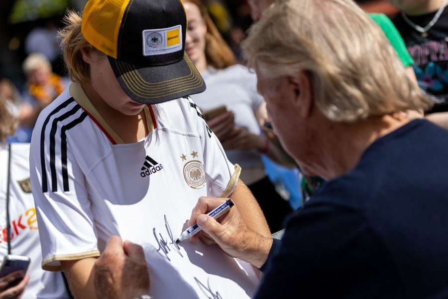 Bundestrainer Horst Hrubesch gibt einem jungen Fan ein Autogramm.