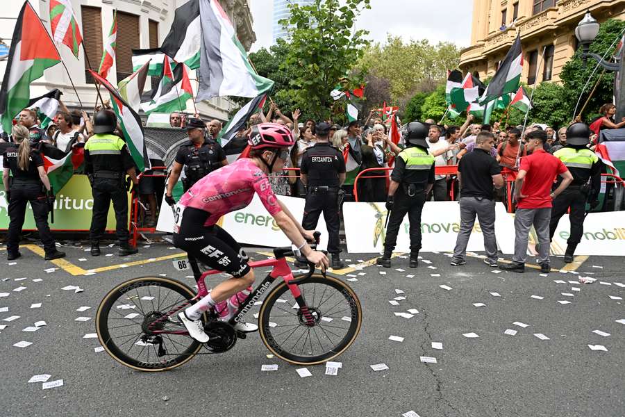 A cyclist competes as pro-Palestinian protesters demonstrate during the 11th stage of the Vuelta a Espana