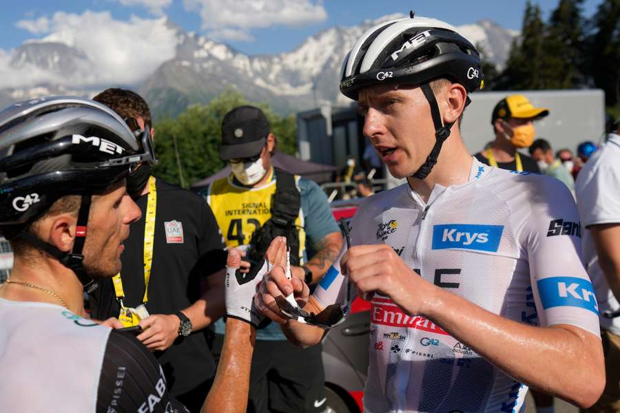 Tadej Pogacar (R) speaks to teammate Rafal Majka in the finish area after the 15th stage of the Tour de France