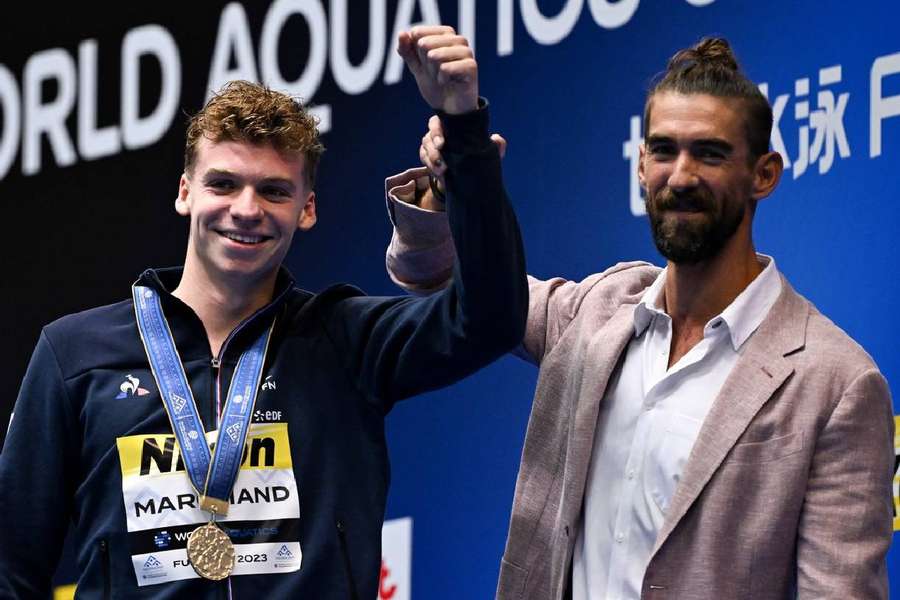 Leon Marchand sărbătorește cu Michael Phelps după finala masculină de 400 m mixt la Campionatele Mondiale de Natație de la Fukuoka