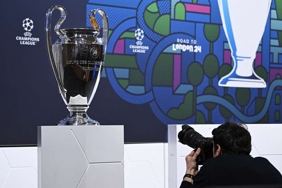 A man takes a photograph of the UEFA Champions League trophy ahead of the 2023/24 UEFA Champions League football tournament round of 16 draw